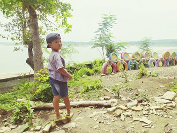 Full length of boy standing by tree against sky