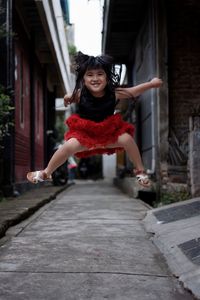 Portrait of smiling girl jumping on street