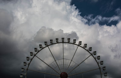 Low angle view of ferris wheel against cloudy sky