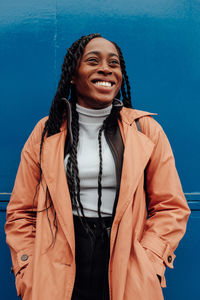 Portrait of smiling young woman standing against blue sky