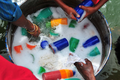 High angle view of people washing plastic glasses in container