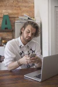 Young man using his smartphone at his kitchen counter