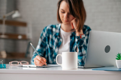 Woman using mobile phone while sitting on table