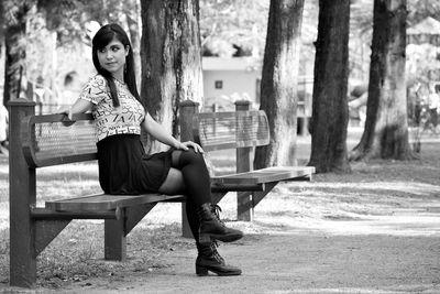 Portrait of young woman sitting on bench in park