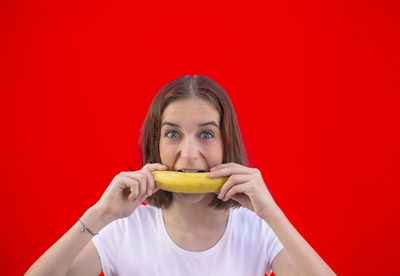 Portrait of woman eating food against red background