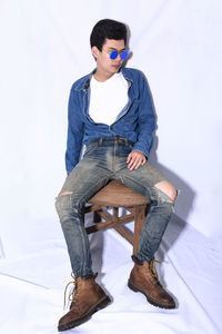Full length of fashionable young man sitting in studio