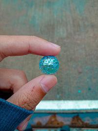 Close-up of hand holding blue ring