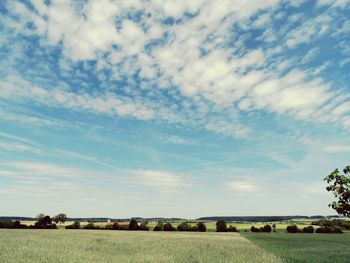 Scenic view of field against cloudy sky