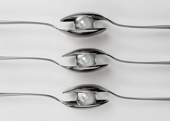 Close-up of spoons with marbles against white background