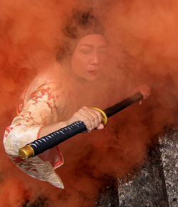 High angle view of woman holding sword while standing amidst smoke on staircase