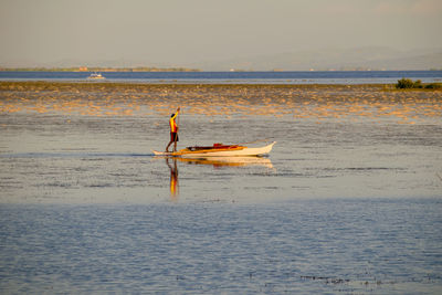 Man on boat in sea against sky