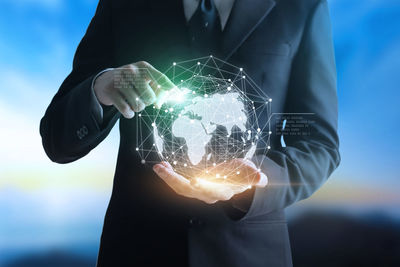 Digital composite image of businessman holding globe