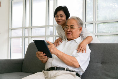 Smiling senor man with wife using digital tablet