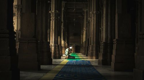 Rear view of woman walking in corridor of historic building