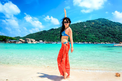 Woman standing at beach against sky