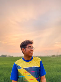 Young man standing against sky during sunset