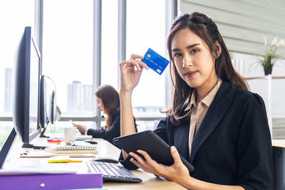 Young woman using phone while sitting on table