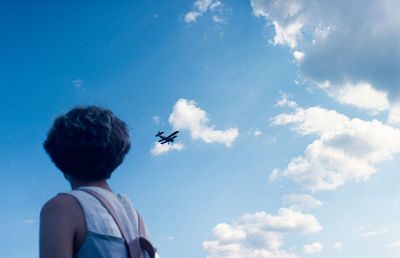 Low angle view of men paragliding against sky