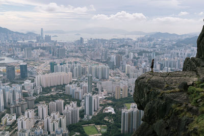 Man standing on cliff against cityscape