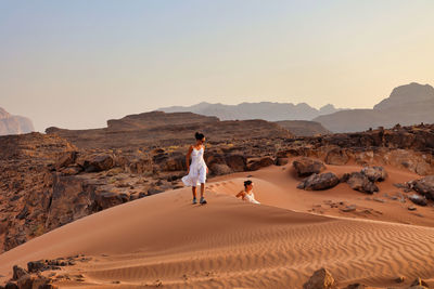 Two girls playing on red dune sand in wadi rum desert at sunset, jordan