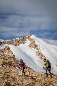 Rear view of people on snowcapped mountain against sky