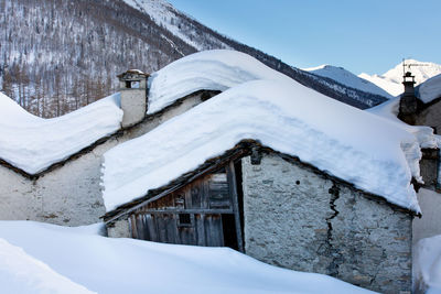 Snow covered houses by mountain against sky