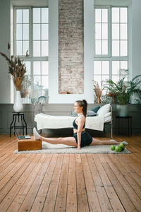 Positive athletic woman with neatly tied hair and tight sportswear stretching 