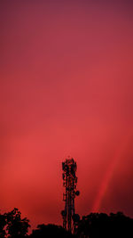 Silhouette of communications tower against orange sky