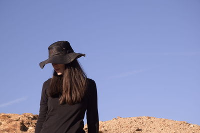 Woman wearing hat standing against clear blue sky