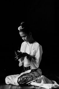 Woman painting against black background