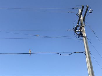 Low angle view of electricity pylon against clear blue sky