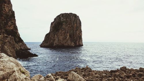 Rocks on sea shore against sky