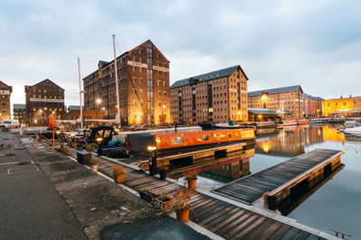 Boats moored at harbor by buildings against sky