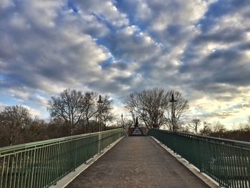 Walkway amidst trees against sky