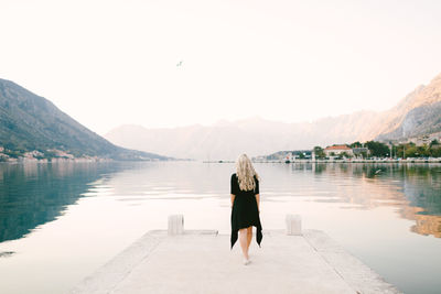 Rear view of woman looking at lake against clear sky