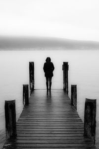 Silhouette woman standing on pier against lake