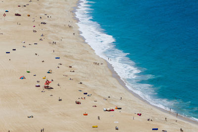 High angle view of people lying on beach with blue sea