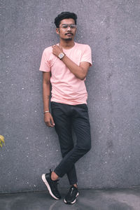 Portrait of young man standing against wall