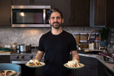 Portrait of smiling man standing in kitchen at home