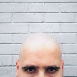 Portrait of bald man against brick wall