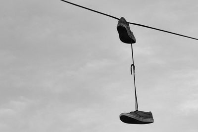 Low angle view of shoes hanging from rope against sky