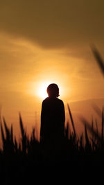 Rear view of silhouette man standing against sky during sunset