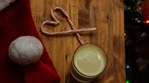 Close-up of drink glass with candy canes and santa hat on table