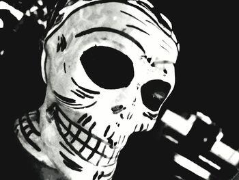 Close-up of person holding mask against black background