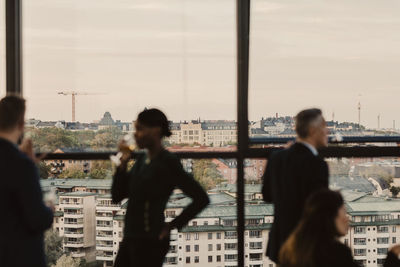 Business people discussing during office party with city in background