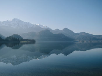 Scenic view of lake and mountains against clear blue sky