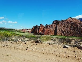 Rock formations on landscape against blue sky