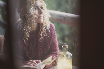 Woman holding book looking away at home