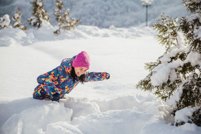 Rear view of woman with snow covered leaves during winter