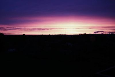 Silhouette houses against sky during sunset